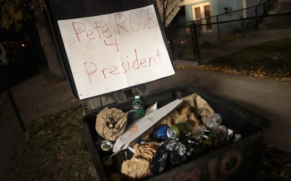 Sign is perched atop a loaded garbage can